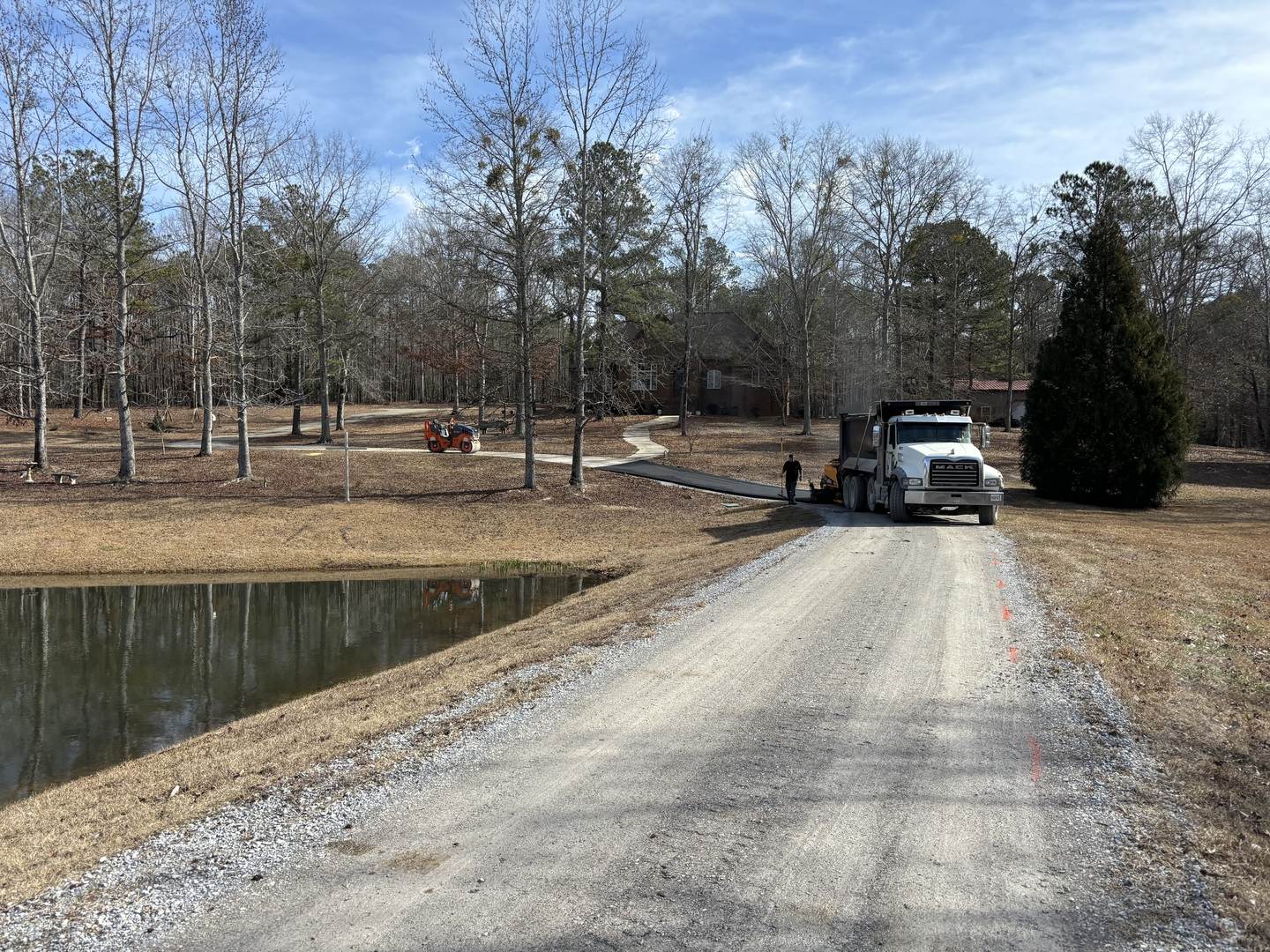 A gravel lane beside a pond with an Apex dump truck at the far end