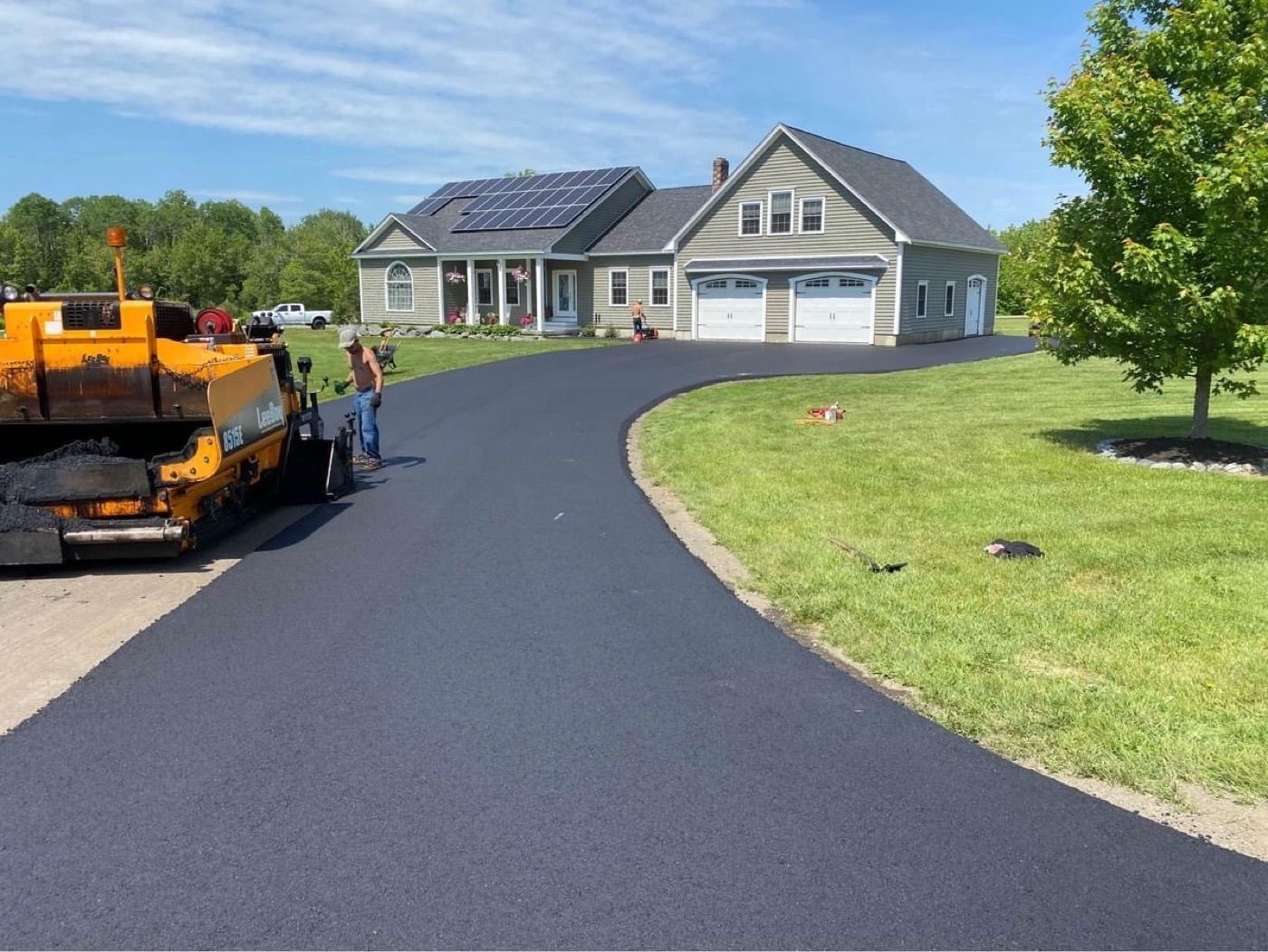 A freshly paved curved driveway leading to a two-car garage