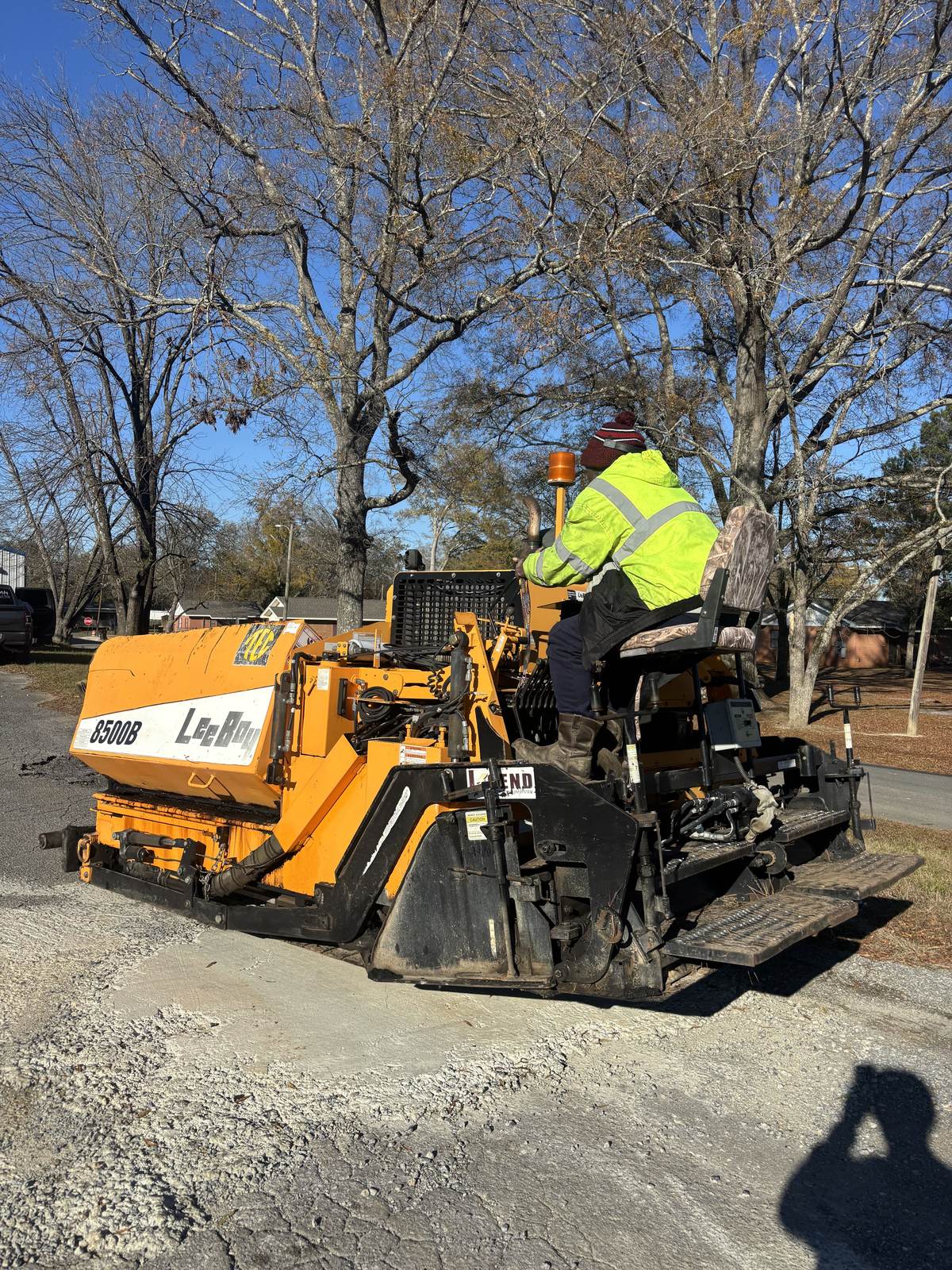An Apex crew member in a safety vest running the paver